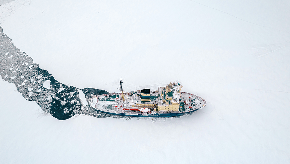 An icebreaker boat cutting across a frozen lake