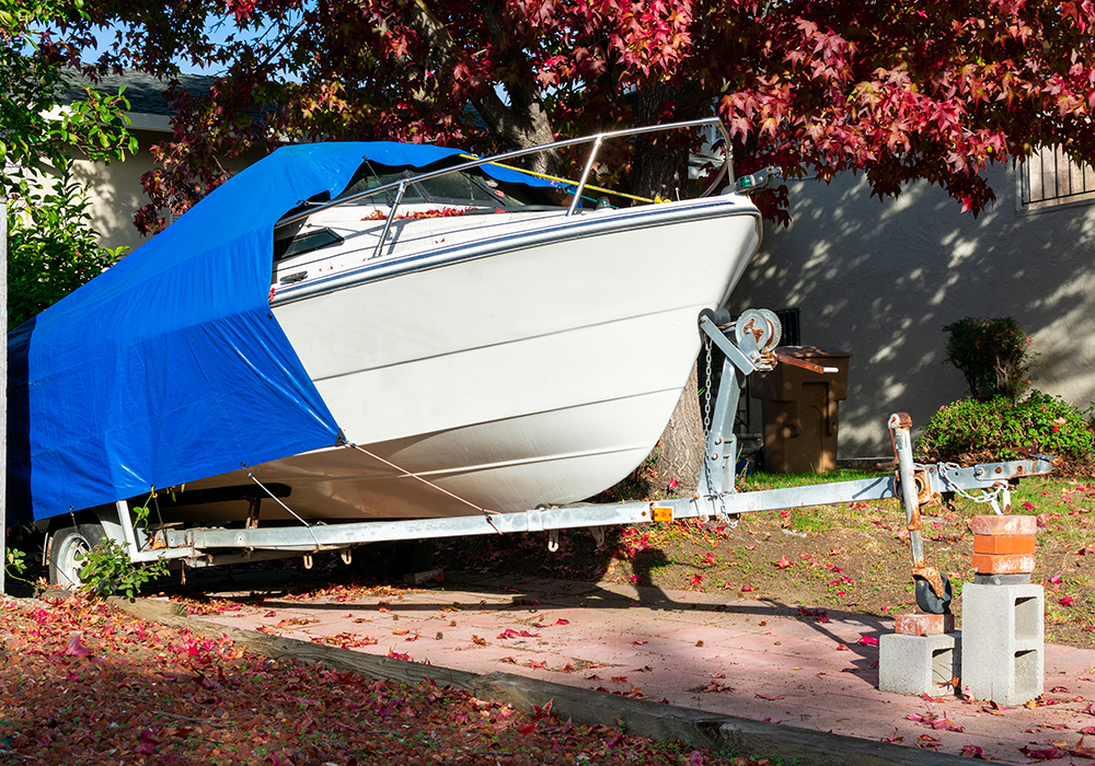 Boat in a driveway covered with a tarp